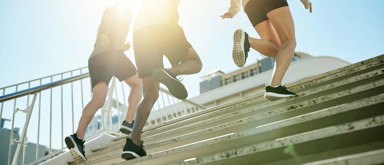 Three people running up some stairs