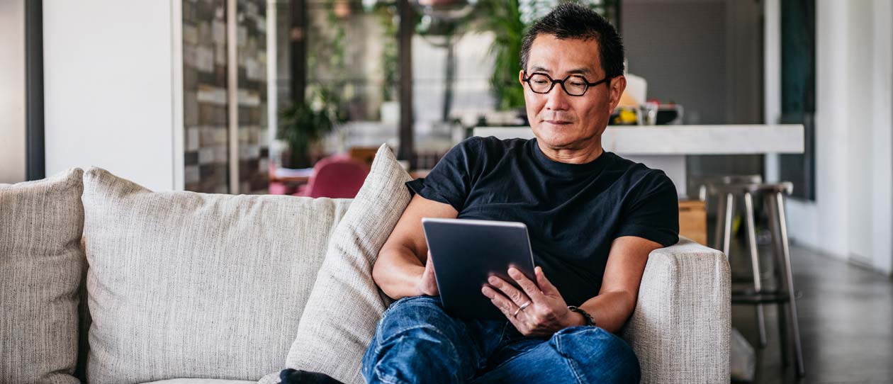 Older man sitting on the couch with an ipad