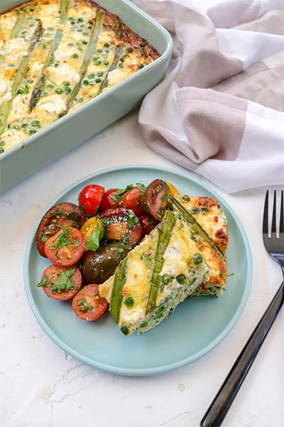 Super green frittata with marinated tomato salad on a plate