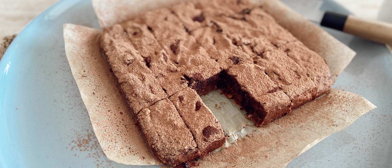 Sweet potato brownies dust with cacao powder on a blue plate