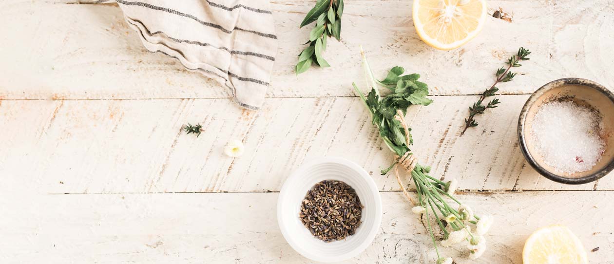 Lavender, lemon, salt and green vegetables on a white timber background