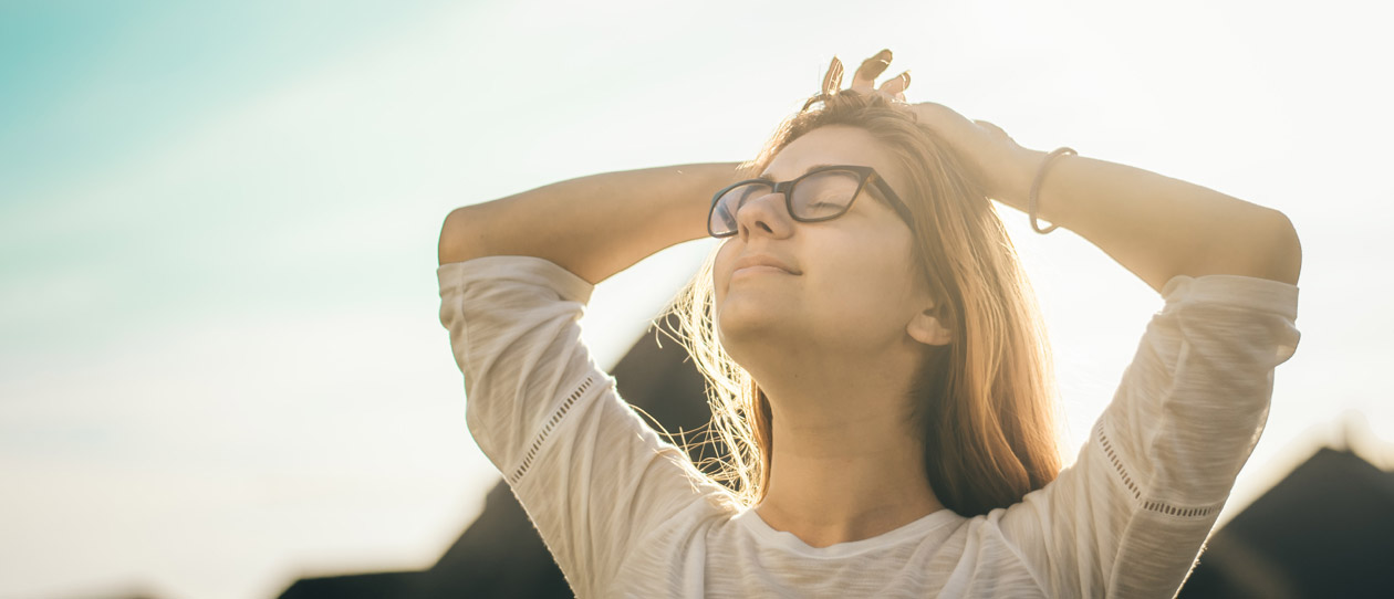 Woman holding her face up into the sun with her eyes closed