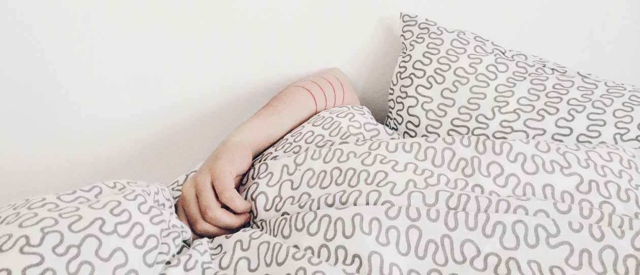 Person sleeping under a white and black bed cover